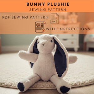 Könnte beinhalten: Ein Plüschhase mit langen Ohren und dunkelblauen Innenohren, Pfoten und Nase. Der Hase sitzt auf einem cremefarbenen Teppich. Der Text oben lautet "BUNNY PLUSHIE SEWING PATTERN". Darunter stehen die Worte "PDF SEWING PATTERN" und "WITH INSTRUCTIONS".