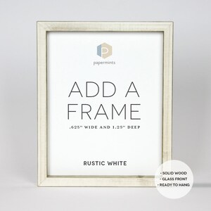 Op de afbeelding: Rustieke witte houten fotolijst met de tekst "ADD A FRAME .625" WIDE AND 1.25" DEEP" en "RUSTIC WHITE". De lijst is gemaakt van massief hout, heeft een glazen voorzijde en is klaar om opgehangen te worden.