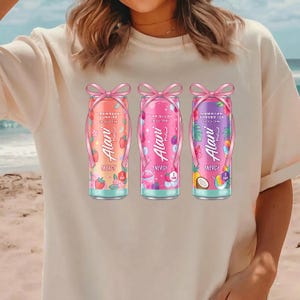 May include: Three Alani Energy drink cans with different flavors: Strawberry Sunrise, Pink Slush, and Hawaiian Shaved Ice. Each can is decorated with a pink bow and features the Alani logo and flavor details. The cans are set against a beach background.