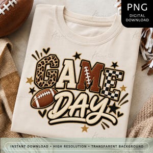May include: A beige t-shirt featuring the text GAME DAY in a multi-patterned design. The letters include leopard print, solid brown, and black and white checkered patterns. A brown football graphic is positioned next to the word GAME.
