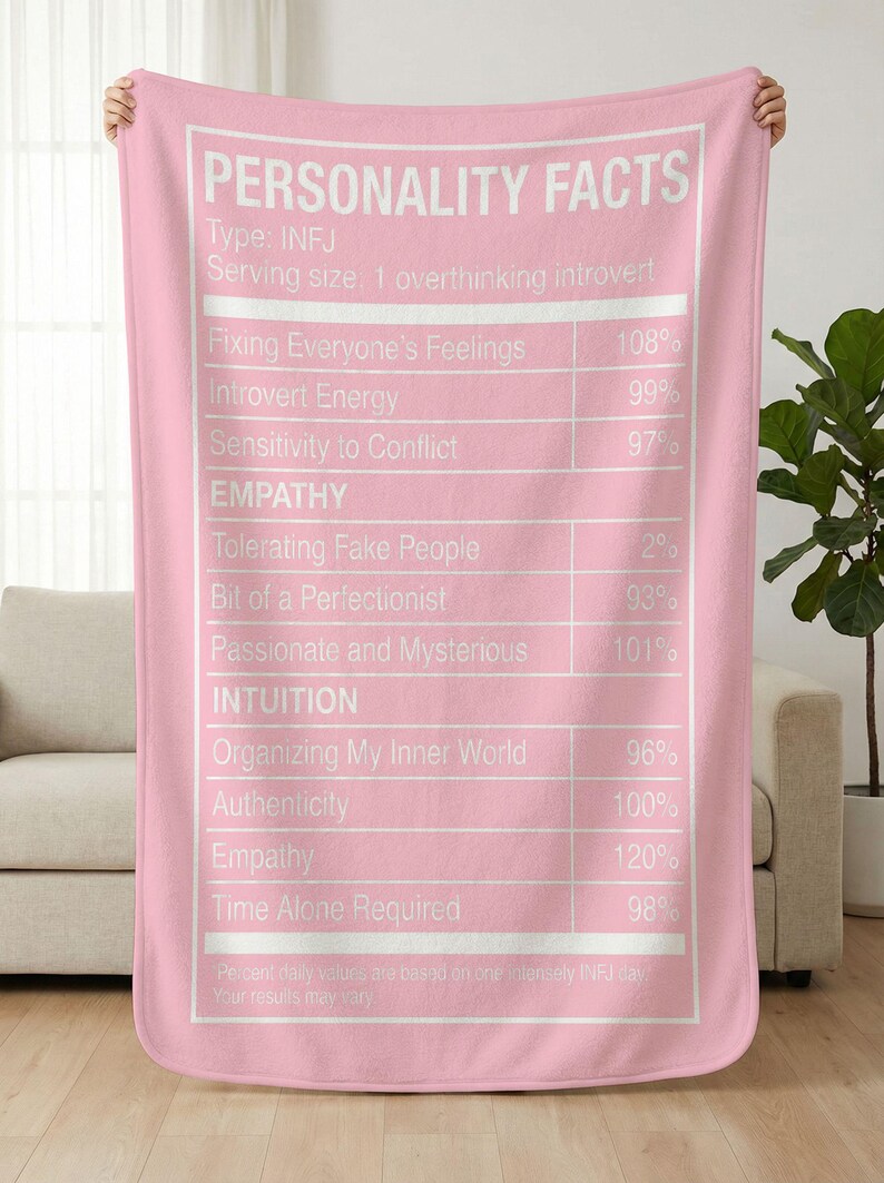 May include: Pink blanket with white text listing "PERSONALITY FACTS" for INFJ personality types. The text includes traits like "Introvert Energy" and "Empathy", with percentage values. The blanket is held up by unseen hands.