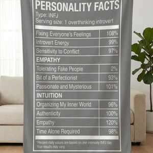 May include: A gray blanket with white text that reads "PERSONALITY FACTS" and a list of traits with percentages, including "Fixing Everyone's Feelings" and "Time Alone Required." The blanket is held up by unseen hands.
