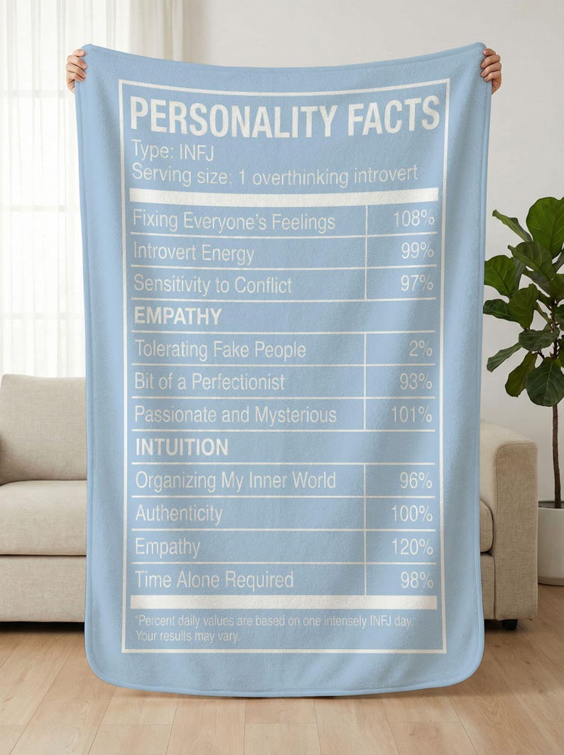 May include: A light blue blanket with white text that reads "PERSONALITY FACTS" and a list of traits with percentages, including "Introvert Energy" and "Empathy". The blanket is held up by a person.