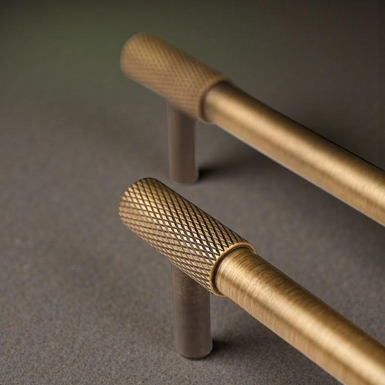 Close-up of knurled brass cabinet pull showing textured grip and brushed brass finish, luxury drawer handle detail