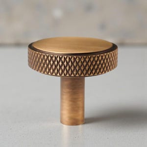 Solid brass knurled cabinet knob photographed on neutral background, textured drawer knob for kitchen and dresser use