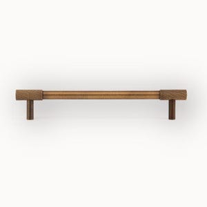 Brushed brass cabinet handle with knurled details, modern wardrobe pull shown from front view