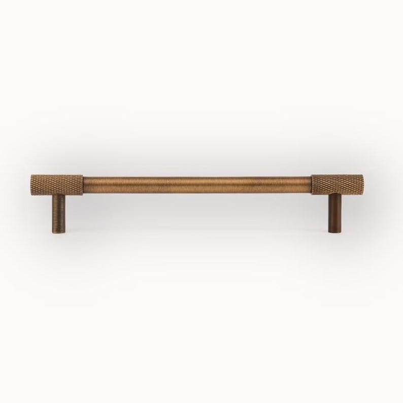 Brushed brass cabinet handle with knurled details, modern wardrobe pull shown from front view