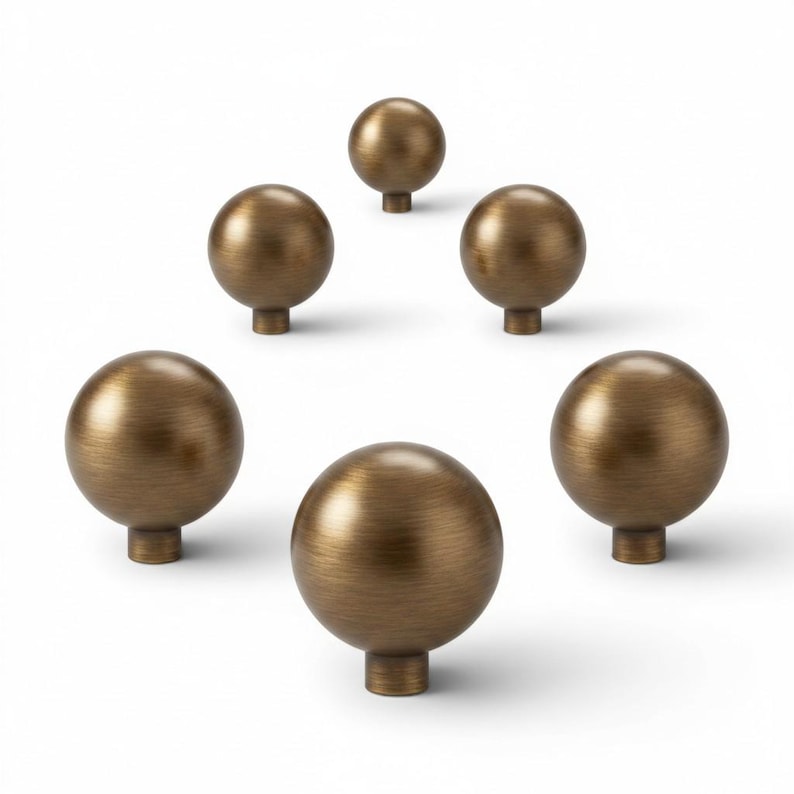 May include: Six bronze-colored cabinet knobs with a spherical design. Each knob has a round base and a smooth, metallic finish. The knobs are arranged against a white background, showcasing their shape and color.