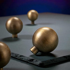 Brushed brass drawer knobs on dark surface, solid round cabinet knobs close-up