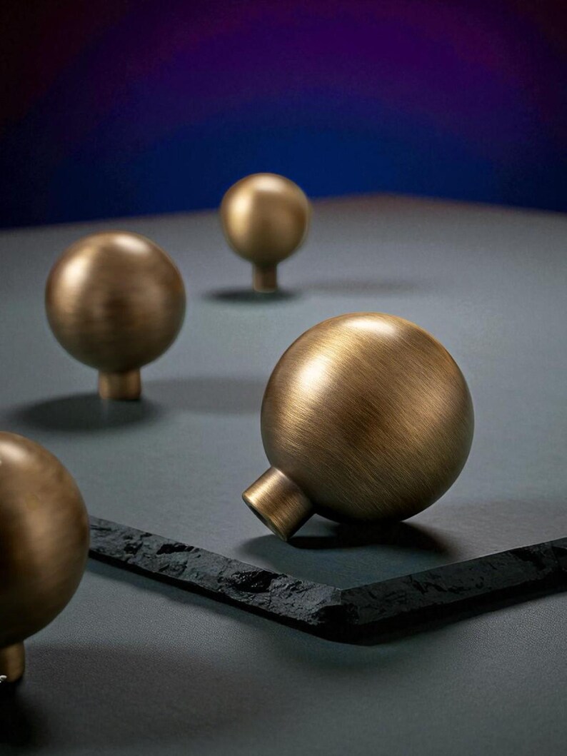 Brushed brass drawer knobs on dark surface, solid round cabinet knobs close-up