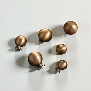 Solid round cabinet knobs grouped together, brushed brass drawer pulls in multiple sizes