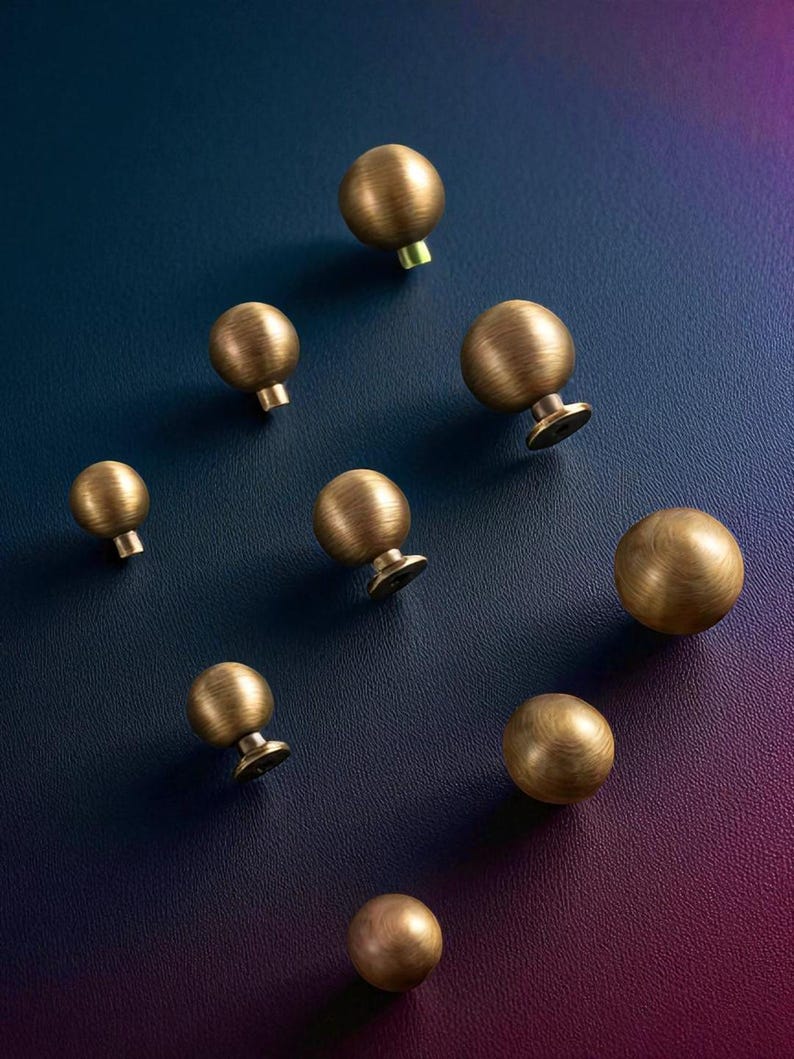 Brushed brass drawer knobs displayed on dark background, solid round cabinet knobs set