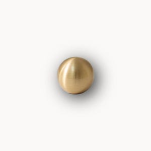 Solid round cabinet knobs grouped together, brushed brass drawer pulls in multiple sizes