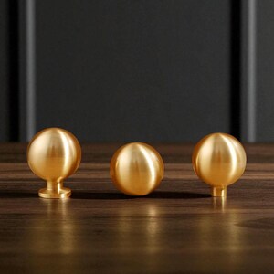 Brushed brass drawer knobs mounted on wooden drawer, solid cabinet knobs for wardrobe and dresser