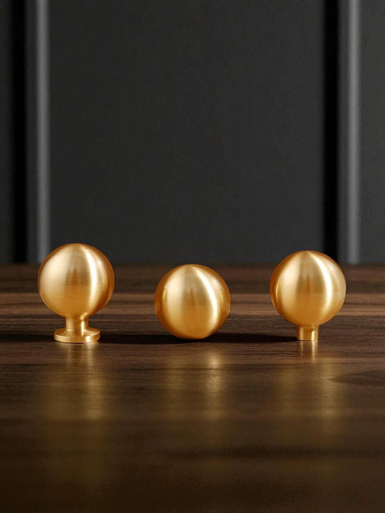Brushed brass drawer knobs mounted on wooden drawer, solid cabinet knobs for wardrobe and dresser