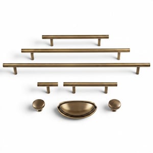 May include: A collection of antique brass cabinet hardware, including bar pulls, knobs, and a cup pull. The hardware is arranged on a white background, showcasing the variety of sizes and styles available for furniture upgrades.