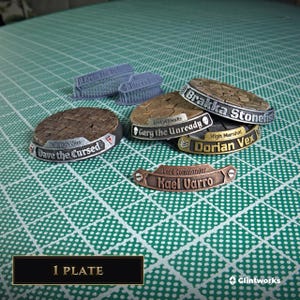 May include: A collection of custom nameplates and base toppers for miniature figures. The pieces feature metallic finishes in silver, gold, and copper, with engraved names including Dave the Cursed, Gary the Unready, Brakkka Stonefist, Dorian Vex, and Kael Varro.