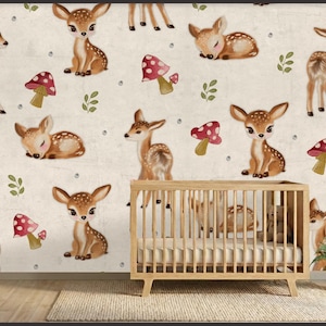 以下が含まれることがあります： クリーム色の背景に、漫画の鹿、赤と白のキノコ、緑の小枝の繰り返し模様が描かれた、保育園の壁画。木製のベビーベッドとマットレスが前景にあり、右側に小さな鉢植えの植物があります。