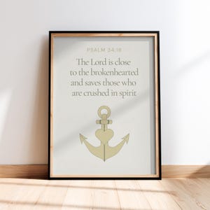 May include: Framed print with the text "PSALM 34:18" and a quote about the Lord's closeness to the brokenhearted. The print features a gold anchor design with a heart in the center. The frame is black.
