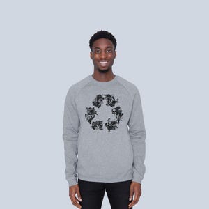 May include: A heather gray long-sleeve sweatshirt featuring a black graphic print on the chest. The graphic is composed of various small, intricate illustrations arranged in the shape of a triangular recycling symbol with rounded corners.
