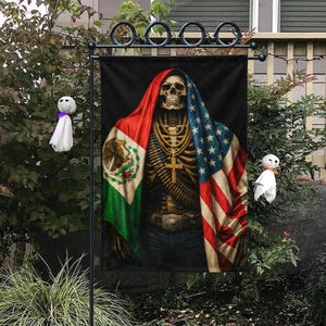 May include: A black garden flag features a skeleton figure draped in the Mexican and American flags. The skeleton wears a gold cross, necklace, and belt buckle. The flag is displayed on a black metal stand, with Halloween decorations in the background.