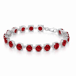Op de afbeelding: Een zilveren armband met een reeks levendige rode edelstenen. De rond geslepen edelstenen zijn gezet in individuele zilveren zettingen, verbonden door kleine zilveren schakels. De armband heeft een sluiting.