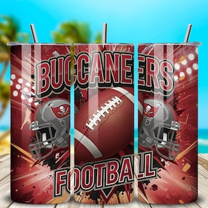 Könnte beinhalten: Drei Edelstahlbecher mit Deckeln und Strohhalmen. Die Becher haben ein rot-schwarzes Design mit den Worten "BUCCANEERS FOOTBALL" und Bildern eines Fußballs und eines Helms mit einem Totenkopf-Logo.