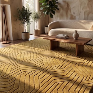 May include: A large rectangular area rug in a deep mustard yellow color featuring a raised, textured geometric pattern of repeating chevron and zigzag lines that create a sense of depth across the entire surface of the floor covering.