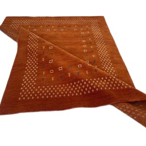 Tapete Boho tecido à mão em tom laranja ferrugem com estampa geométrica tribal, textura macia e aveludada, perfeito para sala de estar e quarto. Feito com mistura de lã ecológica.