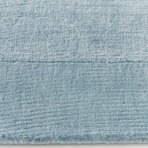 May include: Close-up of a light blue rug with a textured surface. The rug has a soft, plush appearance and a subtle color variation. The texture is visible, with a slight sheen.
