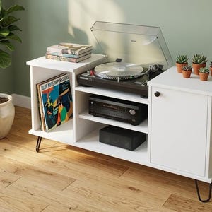 May include: White media console with a record player, audio components, and a small succulent arrangement. The console has a mid-century modern design with black hairpin legs and a cabinet door. A potted plant sits nearby.