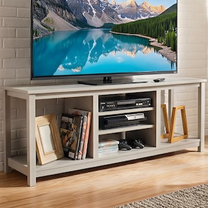 May include: A light gray TV stand with open shelving and a rectangular design. The stand has a large flat-screen TV on top. The shelves hold books, DVDs, a DVD player, a game console, and decorative items.