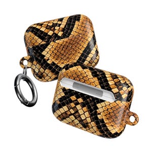 May include: A pair of AirPod cases with a snake skin pattern in shades of brown and black. One case is open, revealing the white interior. A silver carabiner clip is attached to one of the cases.