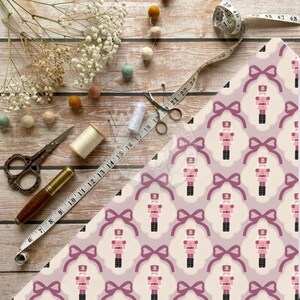 Pink nutcracker ribbon bow fabric print mockup on wooden board with sewing scissors and tape measure.