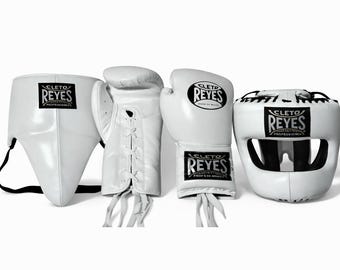 May include: A set of white boxing equipment, including a groin protector, laced gloves, and a head guard. Each piece features the "CLETO REYES" logo in black. The equipment is arranged against a white background.