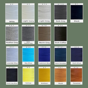 May include: A color chart featuring various shades of thread. The colors include white, light ivory, light grey, dark grey, black, heather grey, dark heather grey, warm grey, dark coffee, lavender blue, sky blue, cadmium blue, dark cerulean, dark blue, dark gray blue, yellow, amber, rust, and caramel.