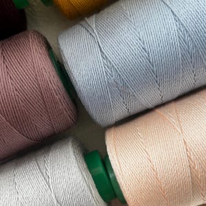 May include: A white ceramic mug with a black handle and the text "But First, Coffee" in a bold, black font. The mug is set against a blurred background, suggesting a cozy setting.