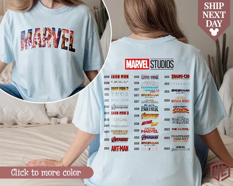 Puede incluir: Camiseta azul claro con la palabra "MARVEL" en un dise&ntilde;o de bloques multicolores en la parte delantera. La parte trasera de la camiseta muestra el logotipo de "MARVEL STUDIOS" y una lista de t&iacute;tulos de pel&iacute;culas y a&ntilde;os de lanzamiento.