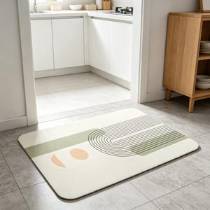 May include: A rectangular floor mat with rounded corners featuring a cream-colored base, sage green rectangular blocks, thin black concentric arch lines, and two soft peach-colored semi-circular and oval shapes arranged in a geometric pattern.