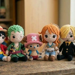 Puede incluir: Una colección de siete muñecos de ganchillo, cada uno representando a un personaje de una popular serie de anime. Los muñecos presentan peinados, atuendos y accesorios distintivos, incluido un barco pirata. Están colocados sobre una superficie de madera.