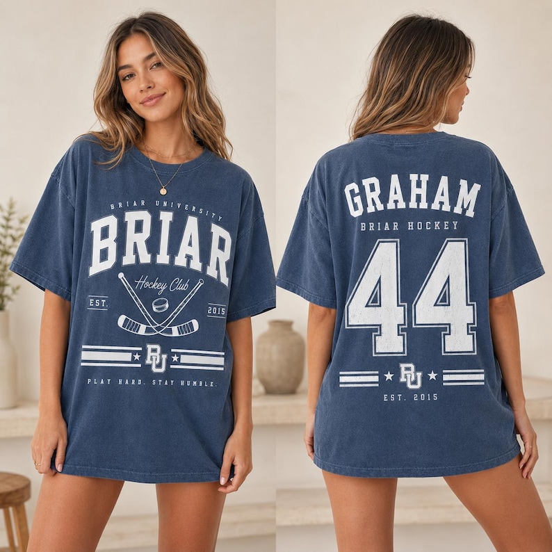 May include: A blue short-sleeve t-shirt featuring white graphics. The front displays 'BRIAR UNIVERSITY', 'Hockey Club', 'EST. 2015', and 'PLAY HARD, STAY HUMBLE' with hockey sticks. The back shows 'GRAHAM', 'BRIAR HOCKEY', and the number '44'.
