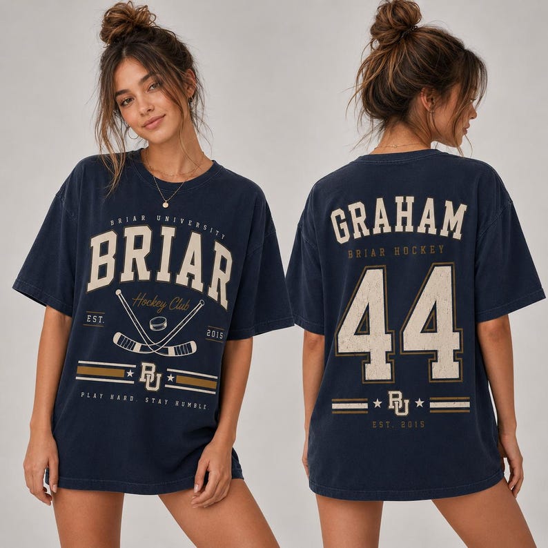 May include: A navy blue short-sleeve t-shirt featuring a distressed cream and gold graphic. The front displays 'BRIAR UNIVERSITY' with crossed hockey sticks and 'EST. 2015'. The back features 'GRAHAM', the number '44', and 'BRIAR HOCKEY'.