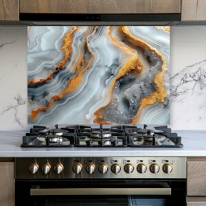 May include: A rectangular kitchen backsplash panel featuring a high-resolution print of agate stone. The design displays swirling layers of white, gray, and translucent crystalline textures accented by vibrant, metallic-toned orange veins.