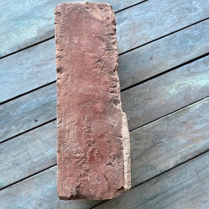May include: A weathered red brick with a rough texture.