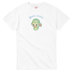 Peut inclure: T-shirt blanc avec une illustration de mouton de dessin animé en vert et rose, et le texte "Sale comme" en bleu. Le t-shirt a un col rond et des manches courtes.