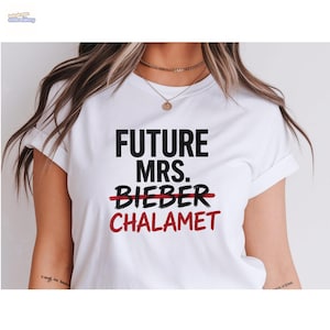 May include: White t-shirt with the text "FUTURE MRS. BIEBER" crossed out and replaced with "CHALAMET" in red. The shirt has short sleeves and a crew neck.