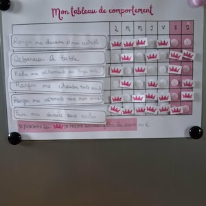 Könnte beinhalten: Eine weiße und rosa Verhaltenstafel mit dem Titel "Mon tableau de comportement" in französischer Sprache. Die Tafel hat Zeilen für Aufgaben und Spalten für Wochentage, mit Kronenaufklebern zur Markierung erledigter Aufgaben.