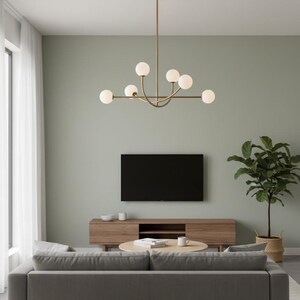 Pu&ograve; includere: Un moderno soggiorno con un divano grigio, un mobile TV in legno e un tavolino rotondo. Un lampadario dorato con luci sferiche &egrave; appeso al soffitto. Un grande televisore a schermo piatto nero &egrave; montato a parete e una pianta in vaso aggiunge verde.