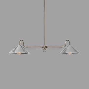 May include: A two-light pendant light fixture with a brushed metal finish. The fixture has a central rod with a horizontal bar extending to two cone-shaped shades. The shades are silver, and the fixture has a warm brass finish.