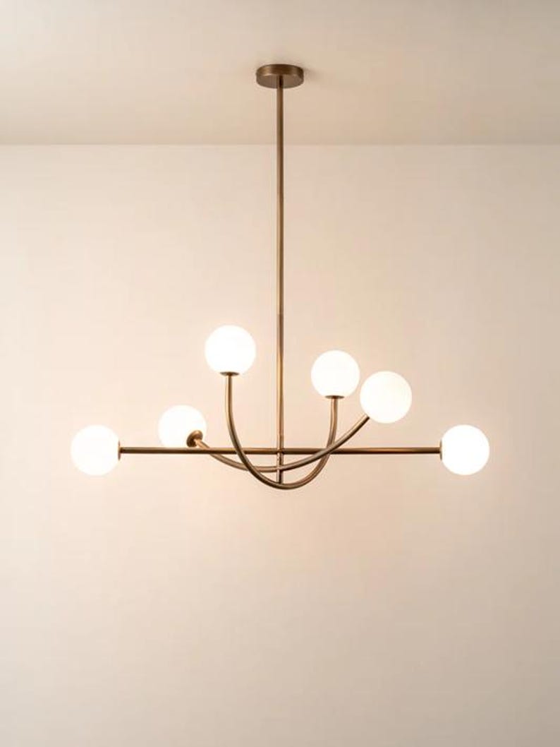 Pu&ograve; includere: Un lampadario moderno con finitura bronzo. L'apparecchio di illuminazione ha sei globi sferici in vetro smerigliato. L'apparecchio &egrave; sospeso al soffitto da un'unica asta.